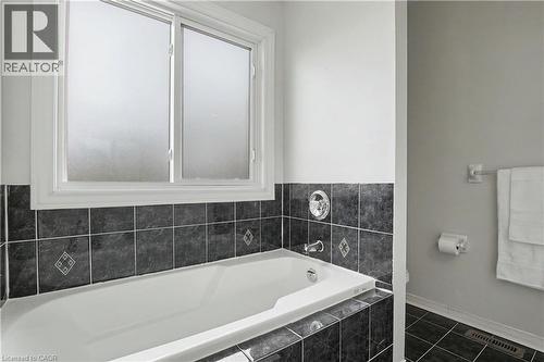 Soaking tub with dark gray tile surround and frosted window - 236 Fitzgerald Crescent, Milton, ON - Indoor Photo Showing Bathroom
