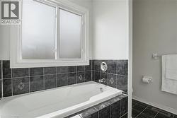Soaking tub with dark gray tile surround and frosted window - 