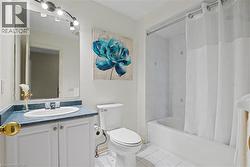 Full bathroom featuring a single vanity with a blue countertop, white cabinetry, track lighting, and a bathtub with white tile surround - 