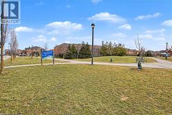 Expansive green space featuring a walking path and mature trees - 