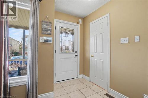 Entryway featuring a white paneled door with decorative glass, neutral wall paint, and square tile flooring - 236 Fitzgerald Crescent, Milton, ON - Indoor Photo Showing Other Room