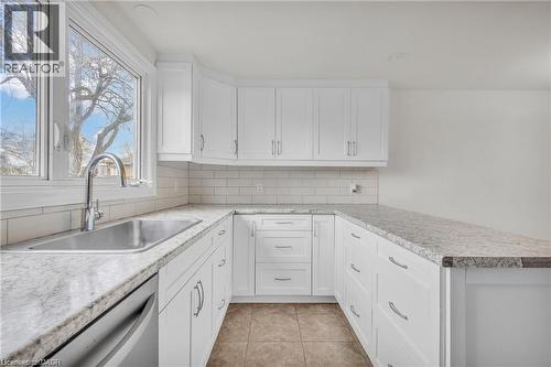 Bright kitchen featuring white shaker cabinetry, speckled countertops, stainless steel undermount sink with gooseneck faucet, subway tile backsplash, and tile flooring - 22 Blackhorne Crescent, Kitchener, ON - Indoor Photo Showing Kitchen With Upgraded Kitchen