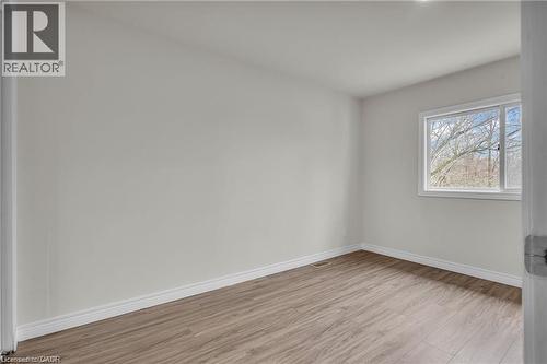 Bright interior space featuring wood-finish flooring, light-toned walls, white baseboards, and a window with a white frame - 22 Blackhorne Crescent, Kitchener, ON - Indoor Photo Showing Other Room