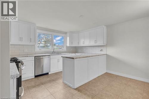 Modern kitchen featuring white shaker-style cabinetry, light-toned granite-look countertops, subway tile backsplash, stainless steel appliances, and neutral tile flooring - 22 Blackhorne Crescent, Kitchener, ON - Indoor Photo Showing Kitchen