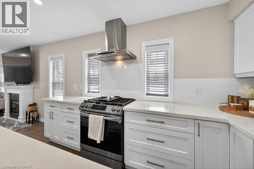 Kitchen featuring a stainless steel range with overhead ventilation, white shaker cabinetry, light-toned countertops, and a white subway tile backsplash - 109 Ray Street N, Hamilton, ON - Indoor Photo Showing Kitchen With Upgraded Kitchen