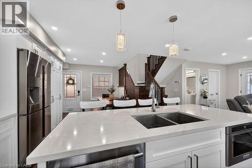 Kitchen island featuring a dual-basin stainless steel sink with a high-arc faucet, light-toned countertop, and integrated under-counter storage - 109 Ray Street N, Hamilton, ON - Indoor Photo Showing Kitchen With Double Sink With Upgraded Kitchen