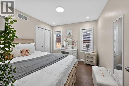 Bedroom with wood-finish flooring, two windows with blinds, a built-in closet with bifold doors, recessed lighting, and a circular flush-mount ceiling light - 109 Ray Street N, Hamilton, ON - Indoor Photo Showing Bedroom