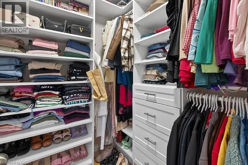 Custom closet system featuring white shelving, multiple hanging rods, and integrated drawers with contemporary pull hardware - 109 Ray Street N, Hamilton, ON - Indoor With Storage
