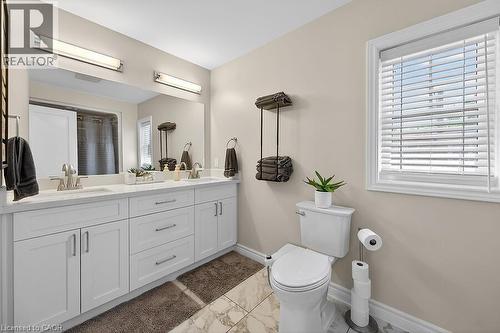 Dual vanity with undermount sinks and chrome fixtures, set against a large mirror with two overhead light bars - 109 Ray Street N, Hamilton, ON - Indoor Photo Showing Bathroom