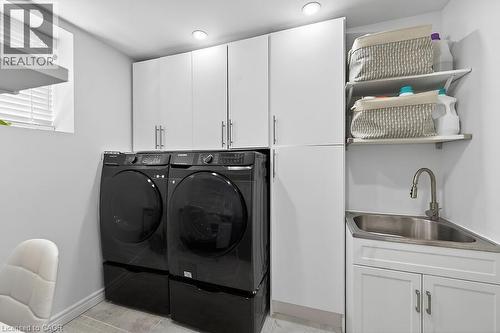 Dedicated laundry area featuring white cabinetry, a utility sink with a gooseneck faucet, and integrated shelving - 109 Ray Street N, Hamilton, ON - Indoor Photo Showing Laundry Room