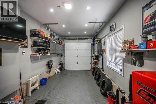 Attached garage featuring a white overhead door, multiple recessed lights, built-in shelving, a window with blinds, and a wall-mounted television - 109 Ray Street N, Hamilton, ON - Indoor Photo Showing Garage