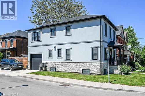 Modern stucco home with a stone facade, featuring a single-car garage and black-framed windows - 109 Ray Street N, Hamilton, ON - Outdoor With Facade