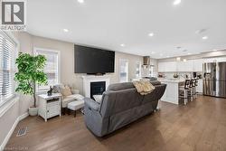 Open-concept living space featuring wood-finish flooring, a white fireplace with mantle, and recessed lighting - 