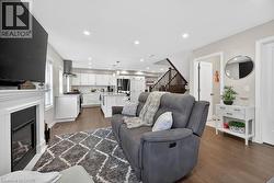 Spacious living area featuring a fireplace with a white mantel, recessed lighting, and wood-finish flooring - 