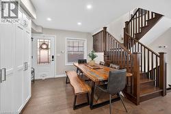 Open-concept dining area featuring wood-finish flooring, recessed lighting, and a prominent wood staircase with matching balusters - 