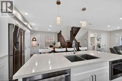 Kitchen island featuring a dual-basin stainless steel sink with a high-arc faucet, light-toned countertop, and integrated under-counter storage - 