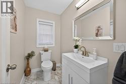 Powder room featuring a single vanity with an integrated sink, a rectangular mirror, a window with blinds, and tile flooring - 