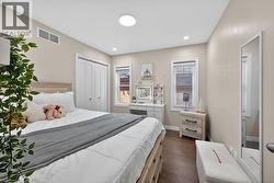Bedroom with wood-finish flooring, two windows with blinds, a built-in closet with bifold doors, recessed lighting, and a circular flush-mount ceiling light - 