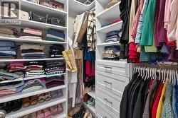 Custom closet system featuring white shelving, multiple hanging rods, and integrated drawers with contemporary pull hardware - 