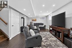 Spacious room featuring wood-finish flooring, a built-in wood stove, recessed lighting, and a white panel door - 