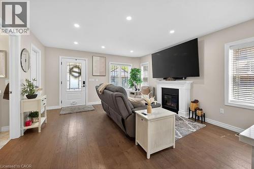 Open-concept living area featuring rich wood-finish flooring, recessed lighting, and a prominent fireplace with a classic white mantel - 109 Ray Street N, Hamilton, ON - Indoor Photo Showing Other Room With Fireplace