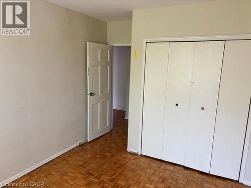Warm wood-finish parquet flooring provides a classic foundation for this space, complemented by neutral wall tones - 2205 King Street E Unit# 1, Hamilton, ON - Indoor Photo Showing Other Room