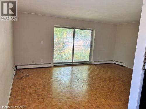 Spacious room featuring wood-finish parquet flooring, light-toned walls, and a large sliding glass door - 2205 King Street E Unit# 1, Hamilton, ON - Indoor Photo Showing Other Room