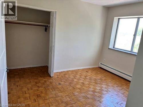 Room featuring wood-finish parquet flooring, a window with a stone sill, and a baseboard heating unit - 2205 King Street E Unit# 1, Hamilton, ON - Indoor Photo Showing Other Room