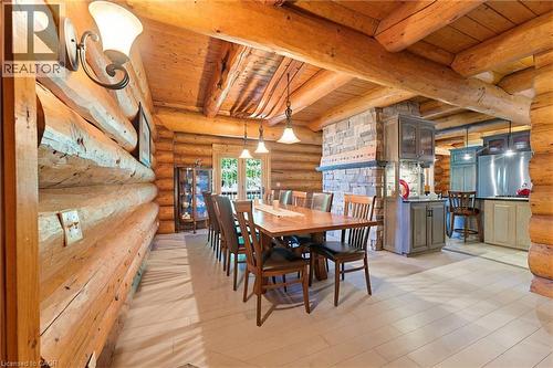 Open-concept main living area with log construction, exposed wood beams, stone accent wall, light-toned flooring, and recessed lighting - 169 James Street, Atwood, ON - Indoor Photo Showing Dining Room