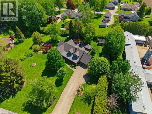 Aerial property overview featuring a multi-gabled main residence, extensive green lawn, mature trees, and a gravel driveway - 169 James Street, Atwood, ON - Outdoor