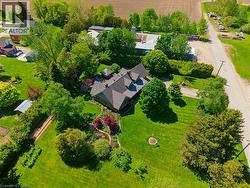 Expansive property featuring a central residence with a dark shingle roof, surrounded by mature trees and manicured lawns - 