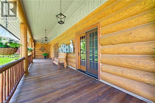 Expansive covered porch featuring log construction, wood-finish flooring, and exposed log railing - 169 James Street, Atwood, ON - Outdoor With Deck Patio Veranda With Exterior