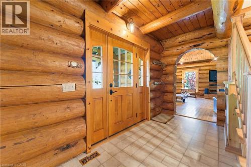 Inviting entry featuring a natural log wall construction, double wood-frame doors with glass inserts, recessed lighting, and a durable tile flooring - 169 James Street, Atwood, ON - Indoor Photo Showing Other Room