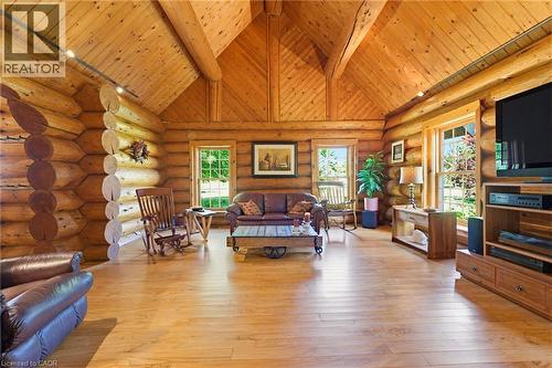 Spacious living area featuring log walls, wood-finish flooring, a vaulted wood-paneled ceiling with exposed beams, and multiple double-hung windows - 169 James Street, Atwood, ON - Indoor Photo Showing Living Room