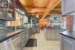Kitchen featuring light grey cabinetry with dark hardware, stainless steel appliances, a mosaic tile backsplash, and dark countertops - 