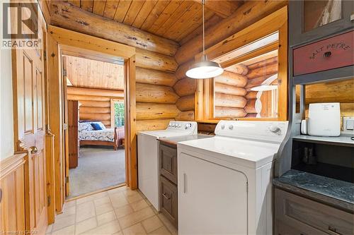Dedicated laundry area featuring a washer and dryer, wood-finish cabinetry, a countertop surface, and log wall construction - 169 James Street, Atwood, ON - Indoor Photo Showing Laundry Room