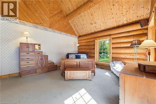 Vaulted wood-paneled ceiling with exposed beams, log wall construction, window with exterior views, and neutral carpet flooring - 169 James Street, Atwood, ON - Indoor