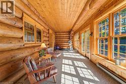 Log home interior featuring exposed log walls, wood-paneled ceiling, multiple large windows, and glass-paned doors - 