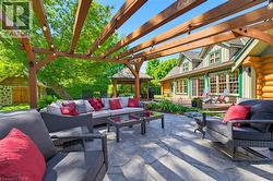 Expansive outdoor patio featuring a stamped concrete surface, a wooden pergola structure with integrated lighting, and a garden area - 