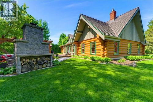Log-style exterior featuring a stone outdoor fireplace with integrated wood storage - 169 James Street, Atwood, ON - Outdoor