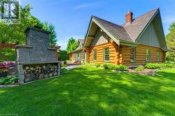 Log-style exterior featuring a stone outdoor fireplace with integrated wood storage - 