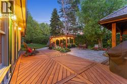 Expansive wood-finish deck with geometric plank pattern, leading to a stone paver patio - 