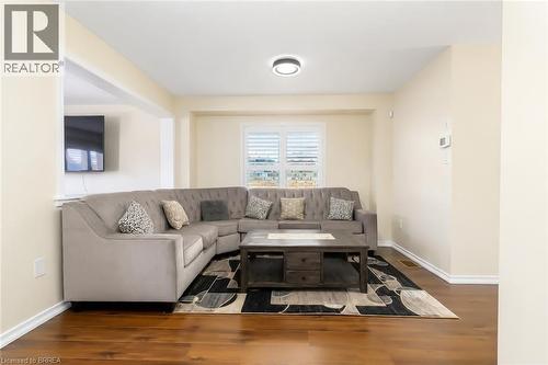 Bright living area featuring wood-finish flooring, light-toned walls, and a window with white shutters - 26 Pollard Street, Brantford, ON - Indoor Photo Showing Living Room