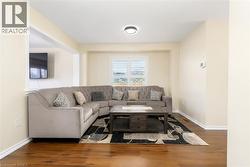 Bright living area featuring wood-finish flooring, light-toned walls, and a window with white shutters - 