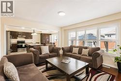 Living area featuring wood-finish flooring and a large window with white plantation shutters - 