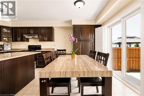Spacious kitchen and dining area with dark wood-finish cabinetry, light-toned countertops, and tile flooring - 26 Pollard Street, Brantford, ON - Indoor