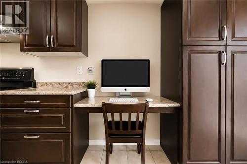 Integrated workspace featuring a built-in desk with a light-toned countertop, flanked by dark wood-finish cabinetry - 26 Pollard Street, Brantford, ON - Indoor Photo Showing Kitchen