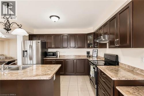 Kitchen featuring dark wood-finish cabinetry, stainless steel appliances, and L-shaped counters with an integrated double basin sink - 26 Pollard Street, Brantford, ON - Indoor Photo Showing Kitchen With Stainless Steel Kitchen With Double Sink With Upgraded Kitchen