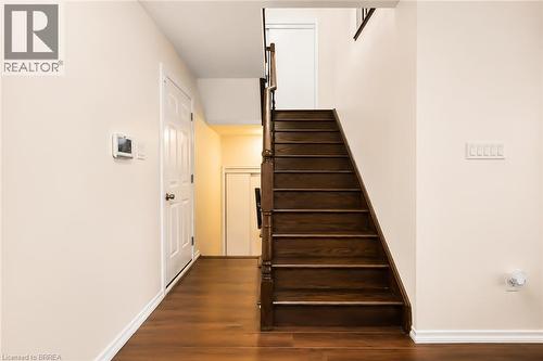 Rich wood-finish flooring and a matching staircase with dark wood newel posts - 26 Pollard Street, Brantford, ON - Indoor Photo Showing Other Room