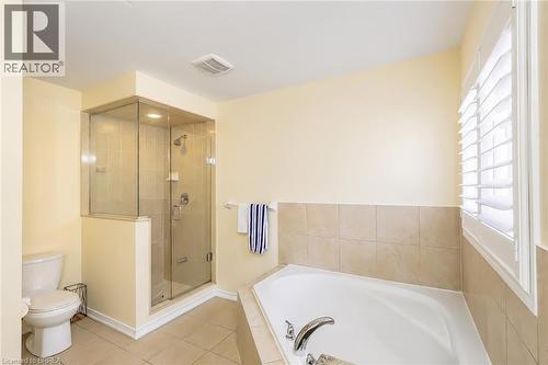Bathroom featuring a corner soaking tub with tile surround, a glass-enclosed shower with tile walls, and a window with plantation shutters - 26 Pollard Street, Brantford, ON - Indoor Photo Showing Bathroom